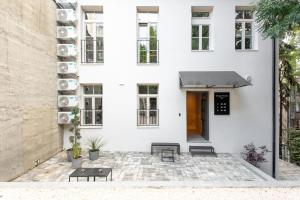 VILLA BASAMAK في سراييفو: منزل أبيض مع مظلة سوداء ومقاعد