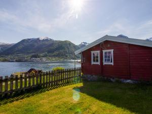 a red house with a fence next to a body of water at Holiday Home Naustvollen - FJS123 by Interhome in Balestrand