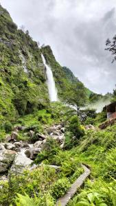 einem Wasserfall an der Seite eines Berges mit einem Fluss in der Unterkunft Birthi Waterfall Homestay in Girgaon