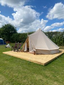 a tent with a bench and a chair on a deck at Roe Deer Meadow at Carr House Farm in Scarborough