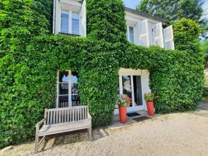 a bench sitting in front of a ivy covered house at La Petardière in Meaux