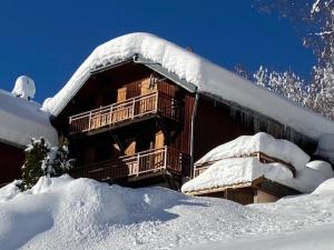 un bâtiment recouvert de neige avec un tas de neige dans l'établissement CHALET LA RIOULE 16 pers, à Doucy