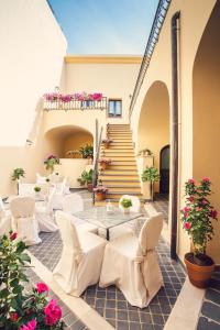 un patio con sillas blancas, una mesa y escaleras en Hotel Il Duomo, en Oristano
