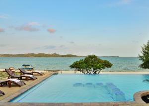 a swimming pool next to the ocean with chairs at Bilene Lodge by Dream Resorts in Vila Praia Do Bilene