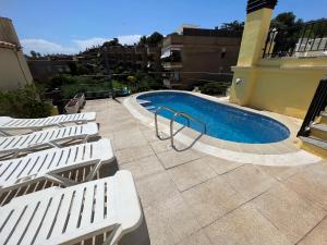 a swimming pool with white lounge chairs next to a building at Apartaments Monjardí in Lloret de Mar