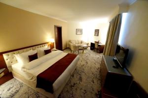 a bedroom with a large bed and a living room at Amman Paradise Hotel in Amman