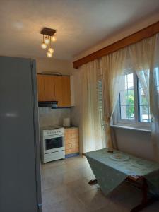 een keuken met een tafel, een raam en een fornuis bij Evelins house Alexandroupoli in Alexandroupoli