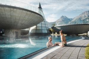 duas mulheres sentadas numa piscina num resort em Chalet Hackl em Sautens