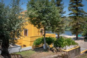 una casa amarilla con árboles delante de ella en Alamal River Club en Gavião