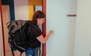 a young woman with a backpack standing next to a door at Snuffel Youth Hostel in Bruges