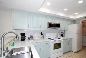 uma cozinha com armários brancos e um frigorífico branco em Franke Plaza unit #1504 condo em South Padre Island