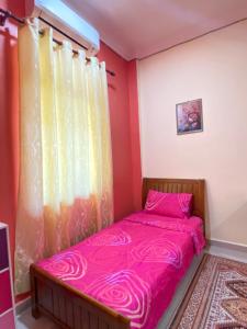 a bedroom with a pink bed and a window at MNOOR HOMESTAY in Marang