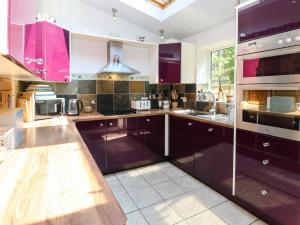 a kitchen with purple cabinets and a large window at Ludd Brook Cottage in Halifax