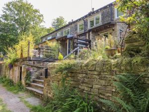 a house on a hill with a stone wall at Ludd Brook Cottage in Halifax