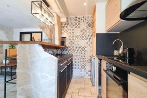 una cucina con armadi neri e piano di lavoro di Appartement Villeneuve Loubet Plage - Spacieux avec Jardin a Villeneuve-Loubet