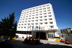 un gran edificio blanco con banderas delante en Amman Paradise Hotel, en Amán