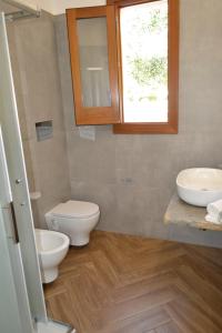 a bathroom with two sinks and a toilet and a window at Bar Gelateria Case Vacanza La Giara in Castelluzzo