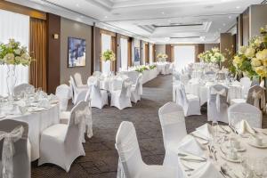 a banquet hall with white tables and chairs and flowers at Crowne Plaza Solihull by IHG in Solihull +61 photos