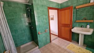 a green bathroom with a sink and a shower at Villa Jolies in Viddalba