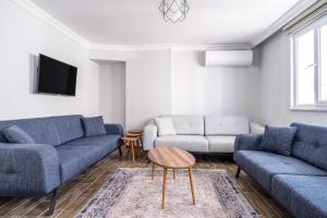 uma sala de estar com dois sofás azuis e uma televisão em Flat w Balcony 10 min to Uskudar Coast em Istambul