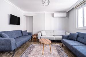 a living room with two blue couches and a tv at Flat w Balcony 10 min to Uskudar Coast in Istanbul