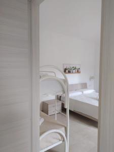 ein weißes Schlafzimmer mit einem Etagenbett und ein weißes Zimmer in der Unterkunft Tenuta Vallina - Golfo di Policastro in Tortorella