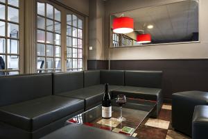 a restaurant with a couch and a bottle of wine at Authentic by balladins Dijon / Marsannay-la-Côte in Marsannay-la-Côte