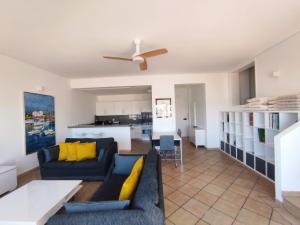 sala de estar con sofá azul y almohadas amarillas en Rocha Paradise, en Portimão