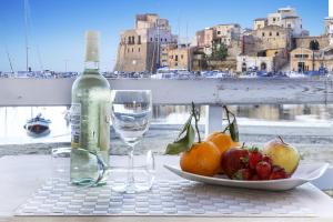 a glass of wine and a plate of food on a table at Hotel Cala Marina in Castellammare del Golfo