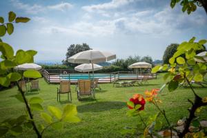a group of tables and chairs with umbrellas and a pool at Santo Pietro Resort in San Gimignano