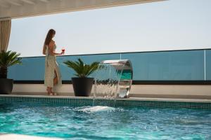 a woman standing next to a swimming pool with a water fountain at THE VIEW Premium Villas in Bar