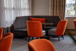 a waiting room with a couch and orange chairs at Carrigaline Court Hotel & Leisure Centre in Cork
