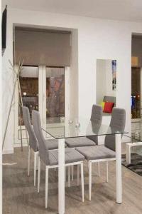 マドリードにあるComodo Y Agradable Apartamento En Madrid Centro 3のダイニングルーム(ガラスのテーブル、椅子付)
