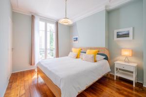 una camera da letto con un grande letto bianco con cuscini gialli di Bastille Trousseau Apartment a Parigi