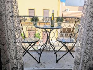 uma mesa com 2 cadeiras e uma garrafa de vinho na varanda em Il Cortile Siciliano Apartments em Trapani