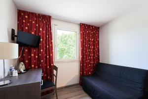 ein Wohnzimmer mit einem Sofa und einem Fenster in der Unterkunft Authentic by balladins Dijon / Marsannay-la-Côte in Marsannay-la-Côte