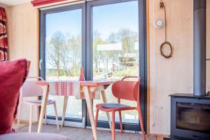 einen Tisch und Stühle in einem Zimmer mit Fenster in der Unterkunft Besonderer Urlaub auf Hausboot TYSTNADEN in Hamburg