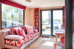 un sofá en una habitación con ventanas en Besonderer Urlaub auf Hausboot TYSTNADEN en Hamburgo