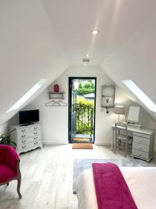 a white attic bedroom with a bed and a desk at The Nest in Rake