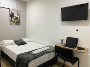 a bedroom with a bed and a desk with a laptop at PRIMAVERA LIVING in Medellín