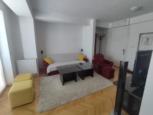 een woonkamer met een bank, een tafel en een tv bij Maja Apartment in Skopje