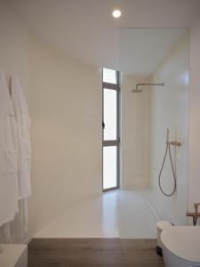a white bathroom with a shower and a toilet at Retiro Costiña Wellness&villas in Santa Comba +16 photos
