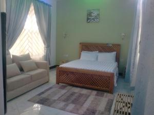 a bedroom with a bed and a couch and a window at BabaJay Family Home in Dar es Salaam