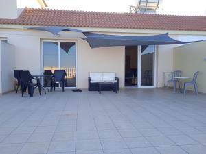um pátio com um guarda-sol azul, cadeiras e mesas em Xylophagou Rest and relax (2) Ayia Napa Larnaca em Xylophaghou