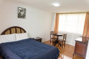 een slaapkamer met een bed, een tafel en een raam bij Hotel International Prestige in Ambato