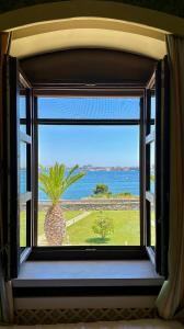 a window with a view of the ocean and a palm tree at Hotel Saraceno Al Faro in Taranto