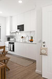 una cocina blanca con armarios y electrodomésticos blancos en Seaside Salty Escape en Nazaré
