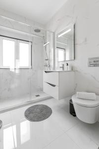 a white bathroom with a shower and a toilet at Seaside Salty Escape in Nazaré