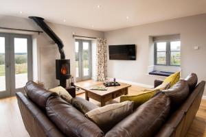 a living room with a leather couch and a fireplace at The Granary at Rothley East Shield in Longwitton