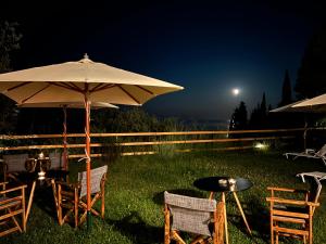 a table and chairs with an umbrella in the grass at Nikoli Apartments in Benitses